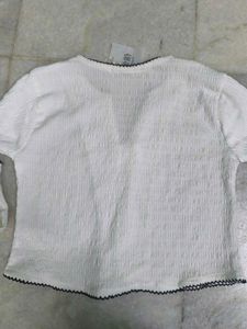 White textured top with black ribbon bows