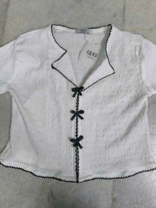 White textured top with black ribbon bows