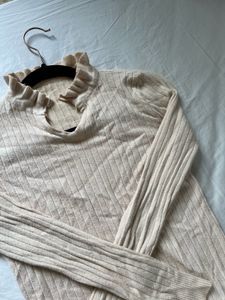 Mock neck featuring a lettuce -edge ruffle trim.
