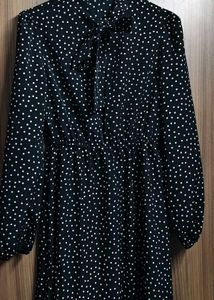 The dress is designed with a bow tie neck