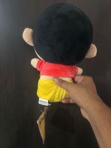 Shin-chan wearing a red shirt and yellow shorts