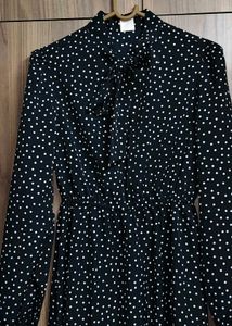 The dress is designed with a bow tie neck