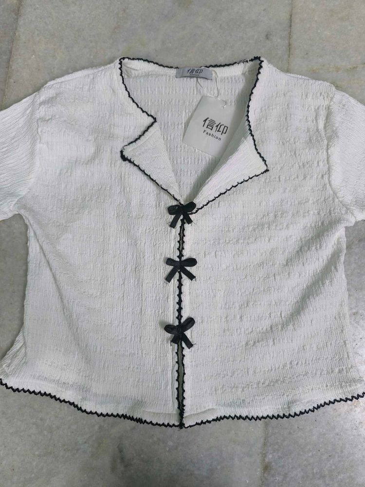 White textured top with black ribbon bows