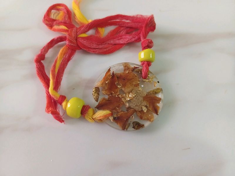 round floral resin rakhi with yellow bead